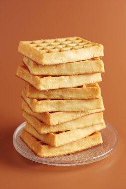 Kahverengi arka planda cam tabakta bir yığın waffle.