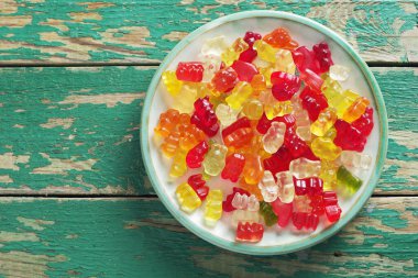 Eski yeşil ahşap zemin üzerinde çok renkli jöle şeker ayıları, fotokopi alanı ile üst görünüm