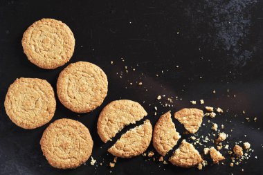 Yulaflı bisküviler siyah metal tepsinin arka planında kırılmış.