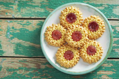 Eski yeşil ahşap bir masada kirazlı bisküvilerin üstten görünüşü. Metin için boşluk