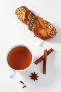 Beyaz arka planda tohumları olan bir fincan çay ve puf böreği.