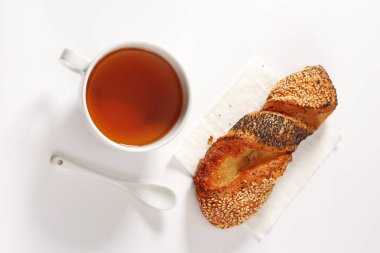 Beyaz arka planda tohumları olan bir fincan çay ve puf böreği.