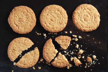 Yulaflı bisküviler siyah metal tepsinin arka planında kırılmış.