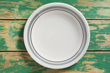 Eski yeşil ahşap masa üzerinde boş temiz tabak, üst manzara