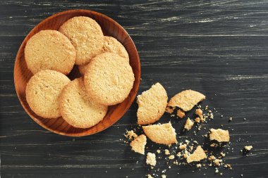 Eski siyah ahşap arka planda, tabakta yulaf ezmeli kurabiyeler.