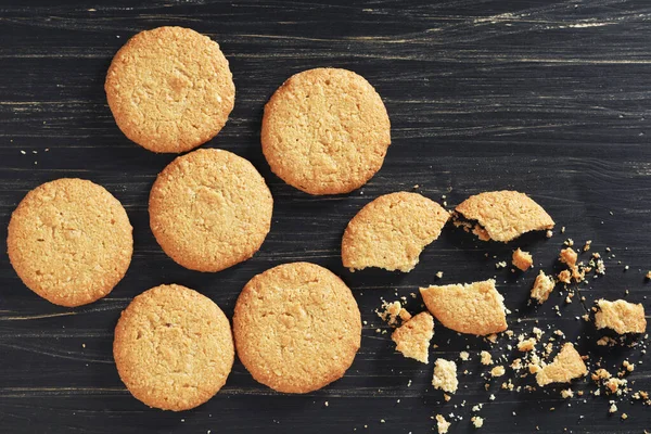 Eski siyah ahşap arka planda yulaf ezmeli kurabiyeler.