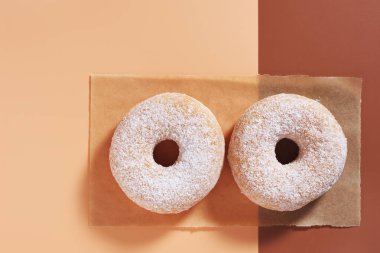 Pudra şekerli klasik donutların üst görünümü, iki renkli arka plan, kopyalama alanı ile 