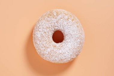 Bej arka planda pudra şekerli klasik çöreğin üst görünümü