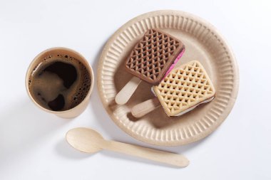 Çubuklu kurabiyeler ve beyaz arka planda tek kullanımlık kağıt kaplarda bir fincan kahve.