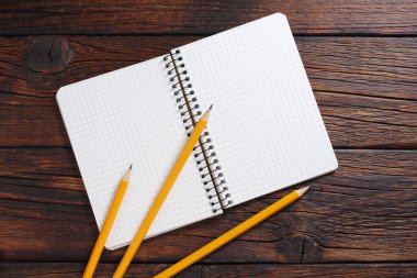 Tahta zemin üzerinde not defteri ve kalemler, üst görünüm