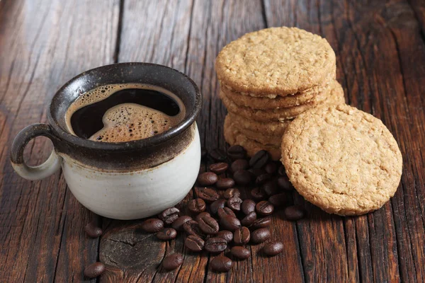 ビスケットクッキーと古い木の背景やテーブルの上のコーヒーカップ — ストック写真
