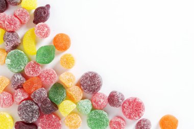 Fruit flavored pastilles with sugar on white background, top view with copy space