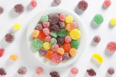 Chewing gum mix with fruit flavor in a plate on a white background, top view