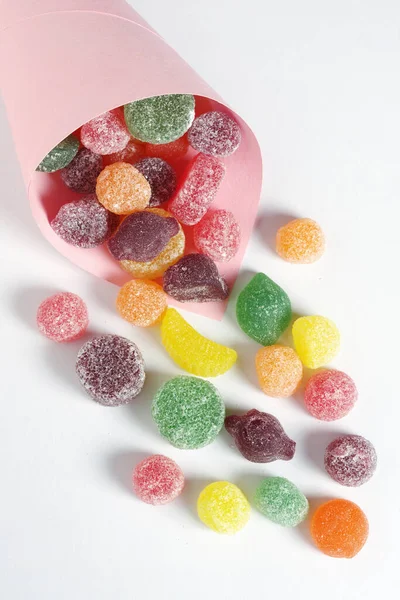 Fruit flavored pastilles with sugar in a paper bag on white background