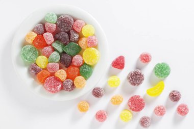 Fruit gum coated with sugar in plate on white background, top view