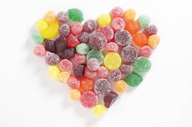 Chewing gum mix with fruit flavor in shape of heart on a white background, top view