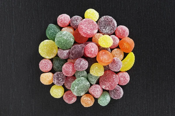 Fruit flavored pastilles on black stone background close up, top view