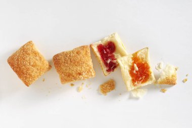 Puff pastry cookies with jam whole and broken on white background, top view