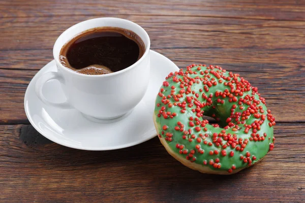 Donut Mit Grünem Zuckerguss Und Tasse Kaffee Auf Holzgrund Nahaufnahme — Stockfoto