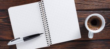 Notepad with pen and a cup of coffee on wooden background, top view