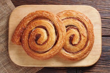 Ahşap arka planda mutfak tahtasına tarçınlı poğaça çörekleri.