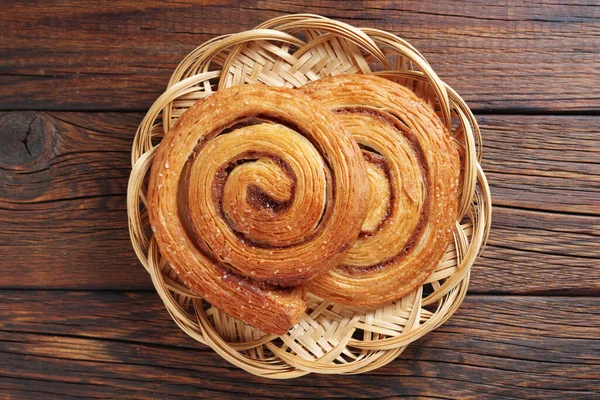 Blätterteigbrötchen Mit Zimt Auf Einem Weidenteller Auf Hölzernem Hintergrund Draufsicht — Stockfoto