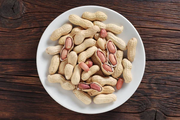 Erdnüsse Auf Einem Teller Auf Hölzernem Hintergrund Draufsicht — Stockfoto