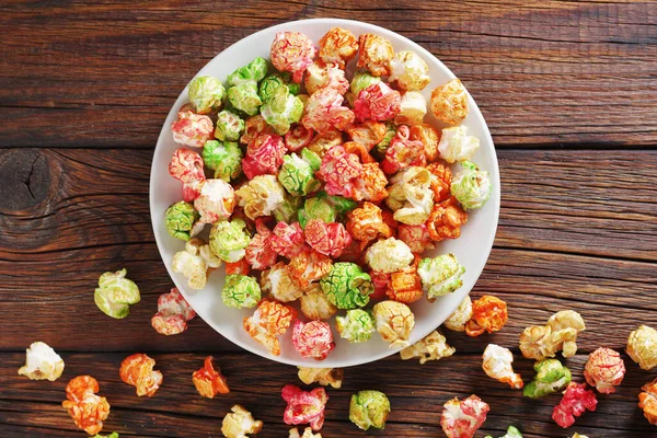 Gekleurde Gekarameliseerde Popcorn Een Plaat Houten Achtergrond Bovenaanzicht Cinema Snack — Stockfoto