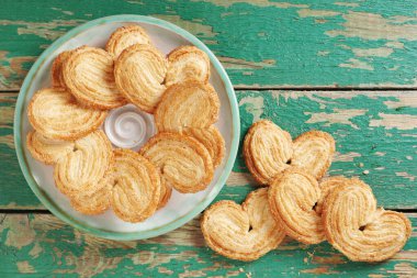 Palmier, ayrıca eski yeşil ahşap arka planda bir tabakta domuz kulağı, üst manzara