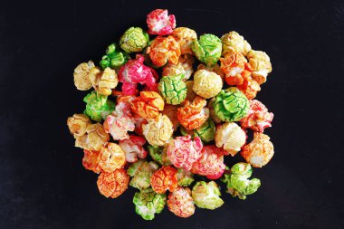 Eski bir siyah metal tepsinin arka planında renkli ve karamelize patlamış mısır yığını. Sinema atıştırmalığı konsepti 