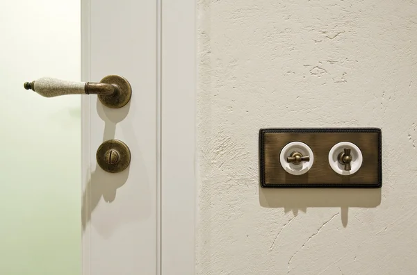 スタイリッシュなヴィンテージ真鍮光スイッチャーとドアのノブ — ストック写真
