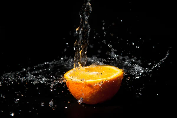 Half orange with splashes of water on a black background Royalty Free Stock Photos