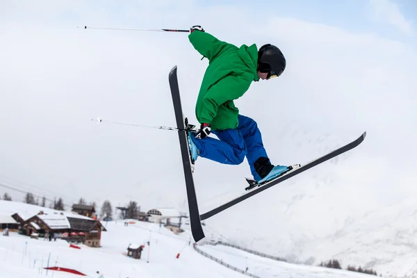 Um saltador de esqui livre, com esquis cruzados contra uma montanha — Fotografia de Stock