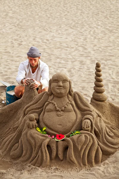 Неизвестный художник работает над своей скульптурой Будды на песке в Лос-Кристиа — стоковое фото