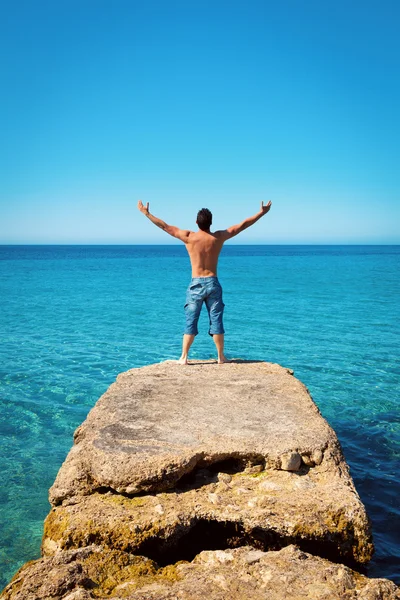 Hombre con los brazos abiertos en el mar tropical azul — Foto de Stock