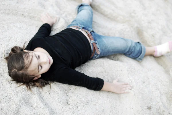 Klein schattig meisje liggend op zand — Stockfoto