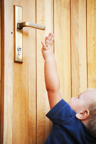 Küçük çocuk kapı kolu ulaşmak için deneyin — Stok fotoğraf