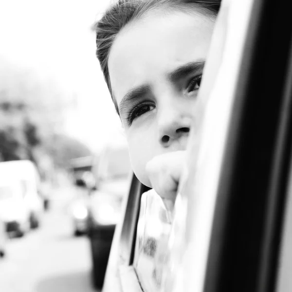 Belle petite fille dans la voiture regardant par la fenêtre. attendant la lumière rouge — Photo