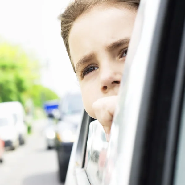 Schöne kleine Mädchen im Auto suchen werfen Fenster. Warten auf die rote Ampel — Stockfoto