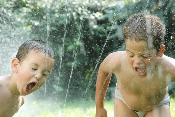 Kleine jongens spelen met stroom van water — Stockfoto