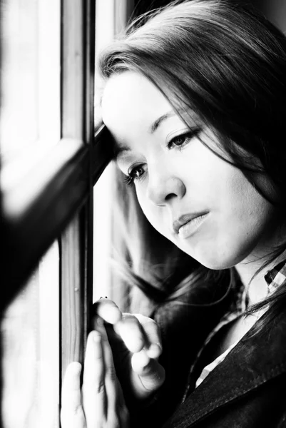 Sad woman against a window — Stock Photo, Image