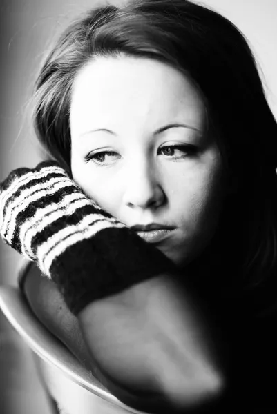 Sad young woman sitting on chair — Stock Photo, Image