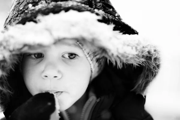 幸福微笑的男孩在吃雪花的冬季衣服 — 图库照片
