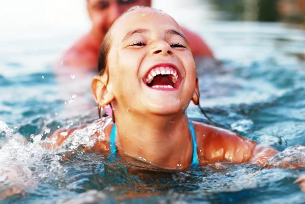 Far og datter leker i havet. – stockfoto