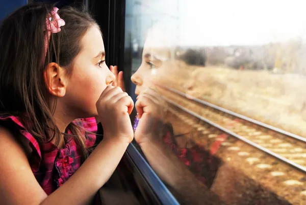 Menina olhando pela janela. Ela viaja de comboio. . Fotografia De Stock