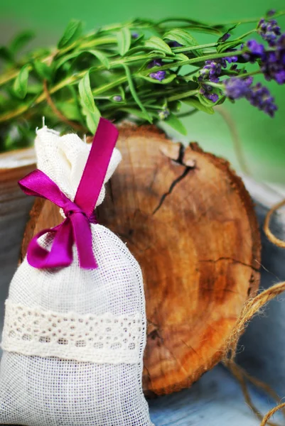 Лавандовый мешок и несколько свежих цветов лаванды на деревянной коробке — стоковое фото