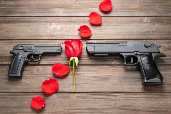 Rose petals and pistol on board. Peace concept.