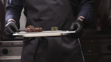 The chef puts cooked meat on the table