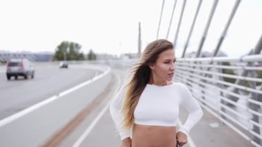 Kız kaykayla dışarıda poz veriyor.