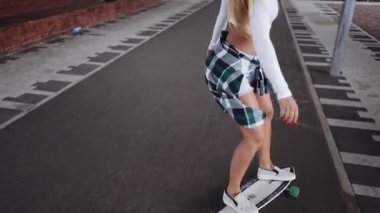 Kız sokakta kaykaya biniyor.